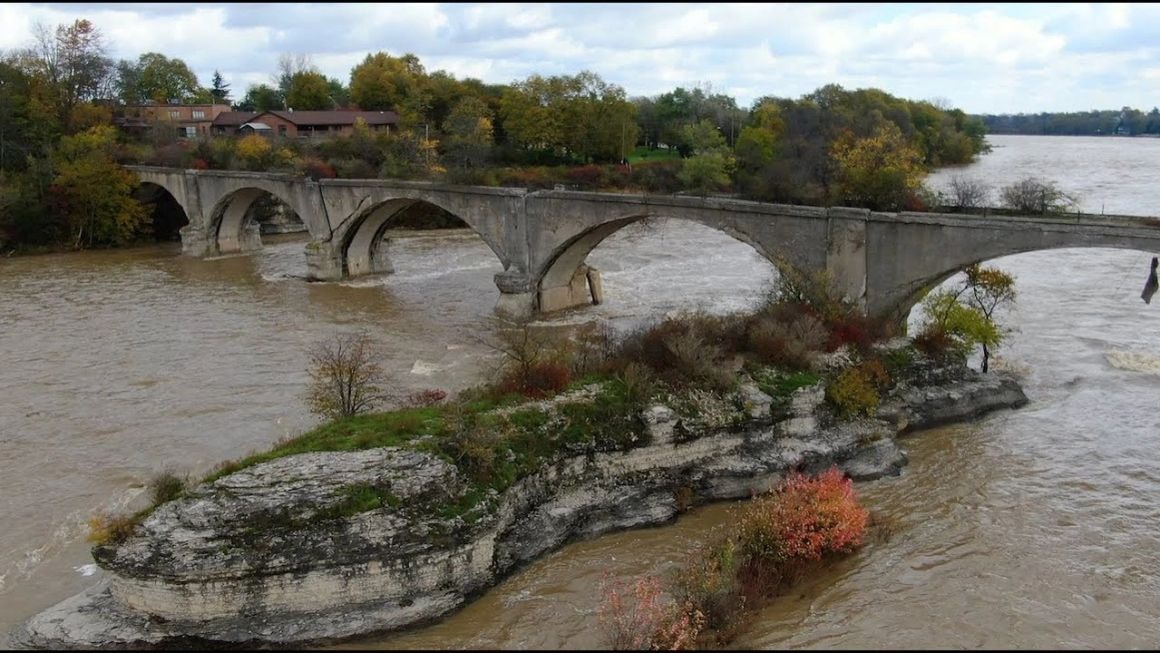 Aerial view of the Interurban Bridge spanning the flooded Maumee River in autumn, Roche de Boeuf rock formation visible